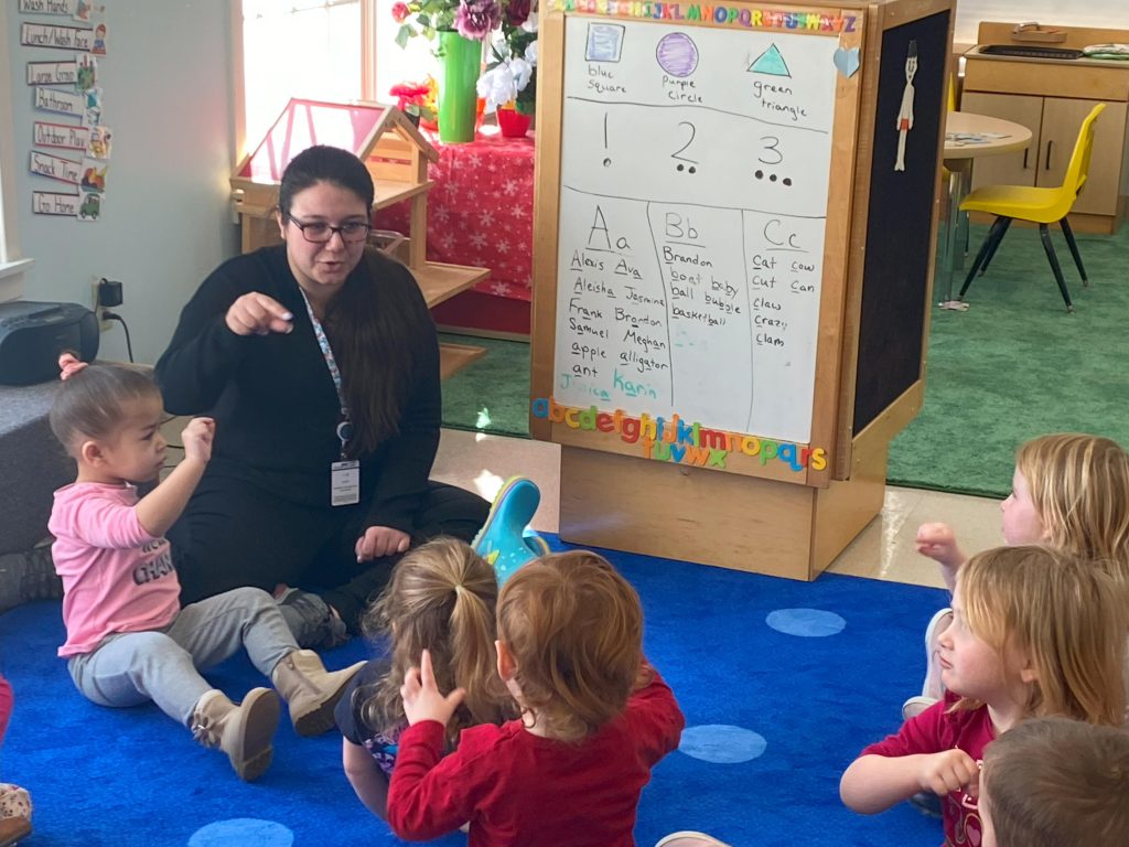 Head Start Teacher using American Sign Language to teach group of pre-school students their letters. 