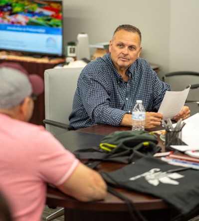 Mike Paris, owner of Turnkey Workplace Services, joins an evening English class in the company showroom. Paris began offering the class free to his employees, through Capital Region Language Center. Paris, right, listens to an employee practice speaking English.