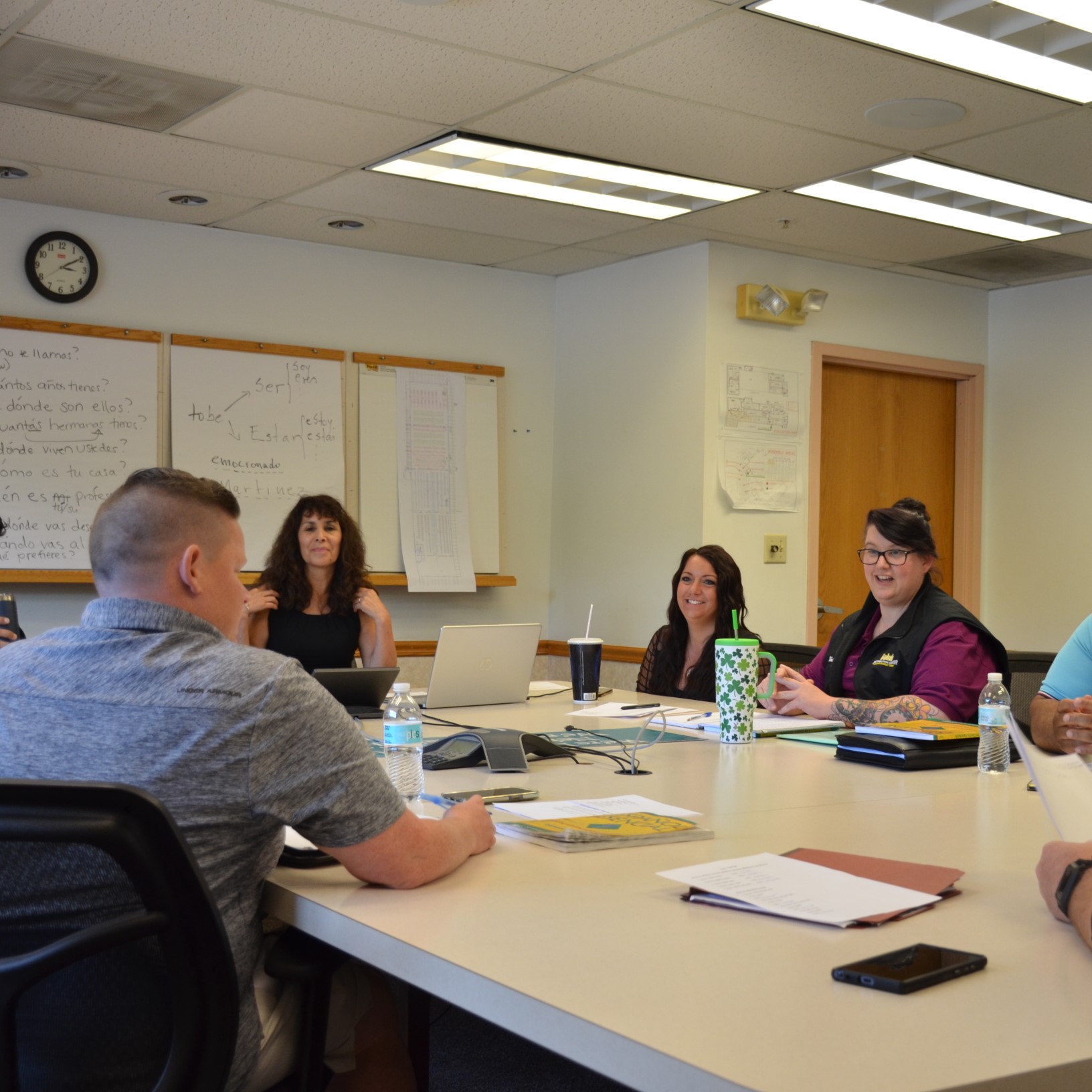 Turnkey employees listen to CRLC's Kim Andersen, during an after-work English class, offered in the company's Troy showroom. Group is seated at tables, with Andersen at the head of the room, speaking to the group.