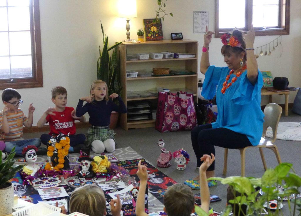 Gloria Batista, Spanish instructor at Capital Region Language Center, leads a song in Spanish and American Sign Language, to teach Malta Montessori students about Dia de los Muertos.