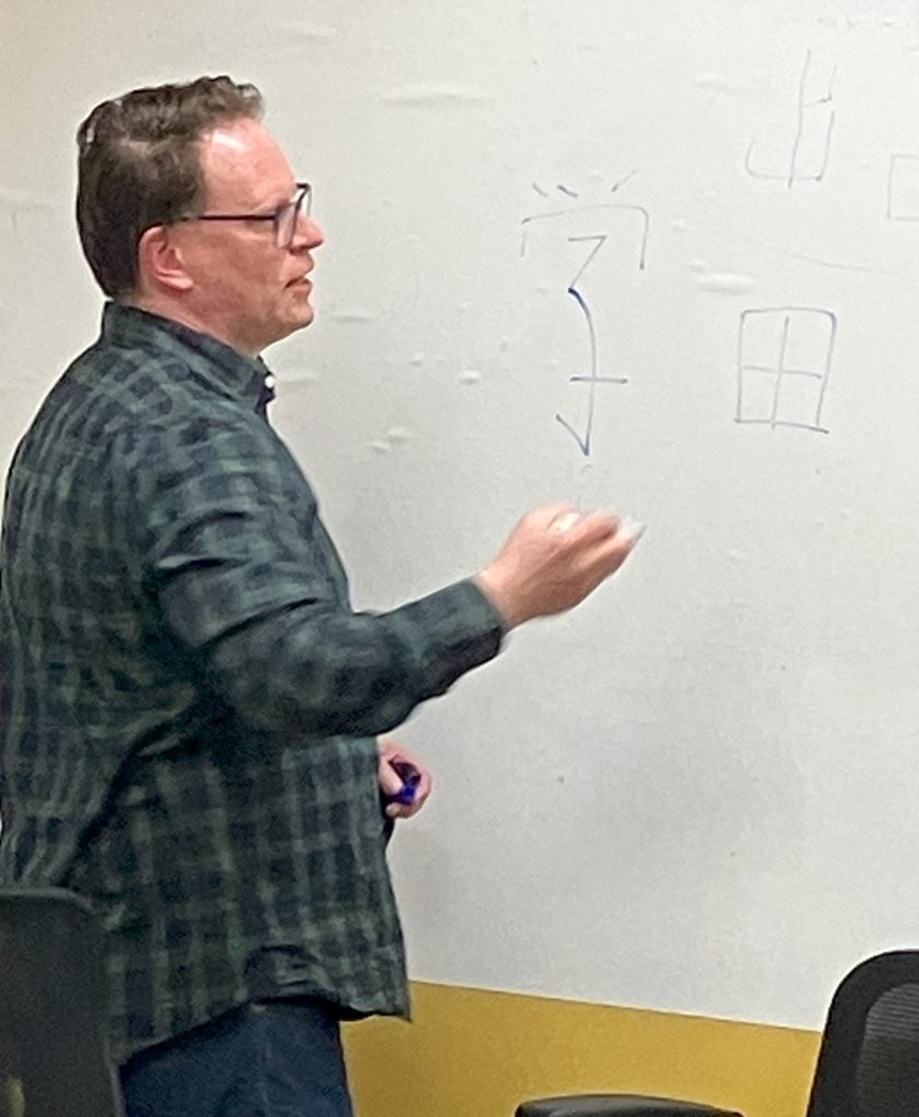 Person writing Japanese characters on whiteboard.