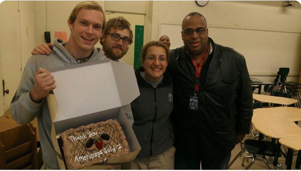Group of four people with arms around each other, holding a cake that says "Thank you Americorps Gold 7" Andrew Poitras used his Spanish class at CRLC to connect with students at the school.