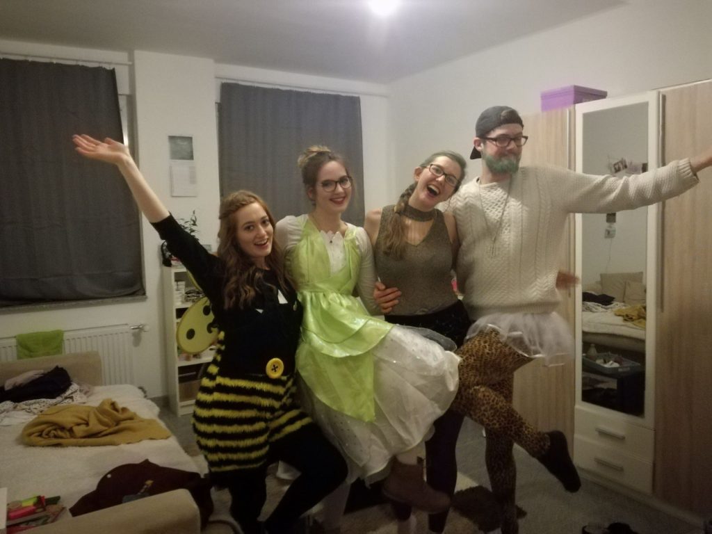 Four friends doing a kickline, dressed for German Karnevale.